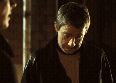 A Man Wearing A Leather Jacket Looks Down At Something GIF