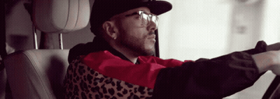 A Man Wearing A Leopard Print Jacket And Glasses Is Driving A Car GIF