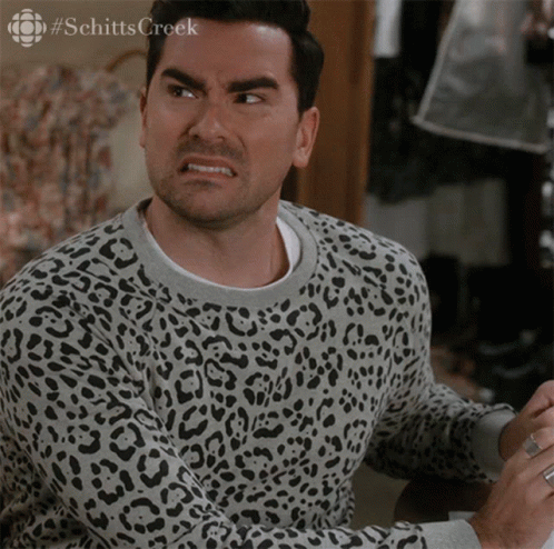 A Man Wearing A Leopard Print Sweater Has The Word Schitts Creek On The Bottom Left GIF