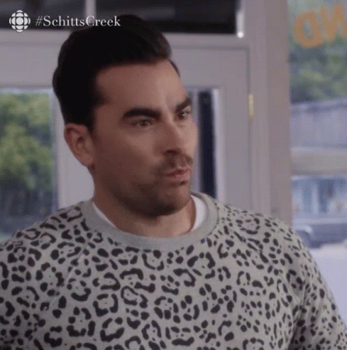 A Man Wearing A Leopard Print Sweater Is Looking At The Camera . GIF