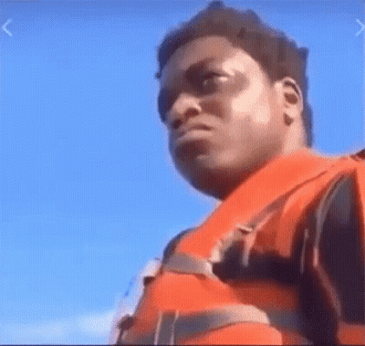 A Man Wearing A Life Jacket Is Standing On A Boat . GIF