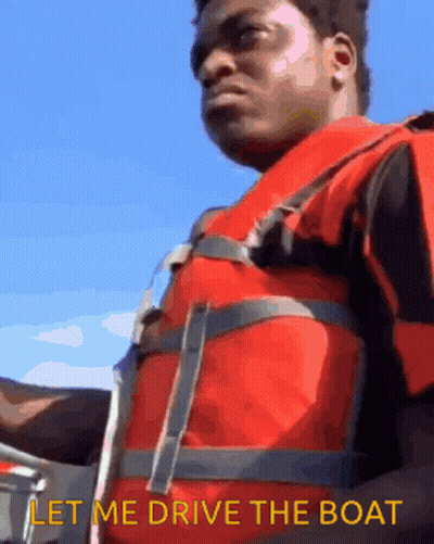 A Man Wearing A Life Vest Says Let Me Drive The Boat GIF