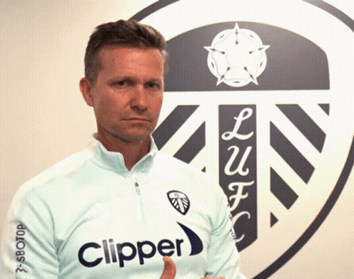 A Man Wearing A Light Blue Clipper Shirt Stands In Front Of A Logo GIF
