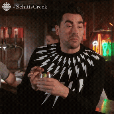 A Man Wearing A Lightning Bolt Sweater Holds A Glass GIF
