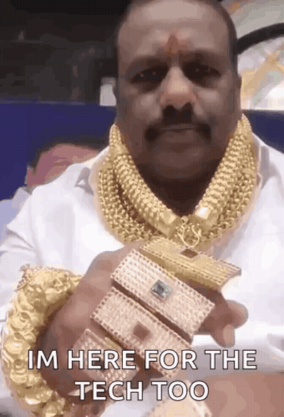 A Man Wearing A Lot Of Gold Jewelry Is Holding A Bracelet That Says I 'M Here For The Tech Too . GIF