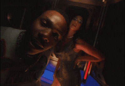 A Man Wearing A Louis Vuitton Sweater Stands Next To A Woman In A Dress GIF