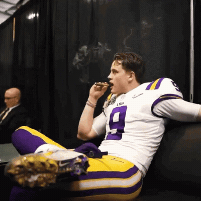 A Man Wearing A Lsu Jersey Is Smoking A Cigar GIF