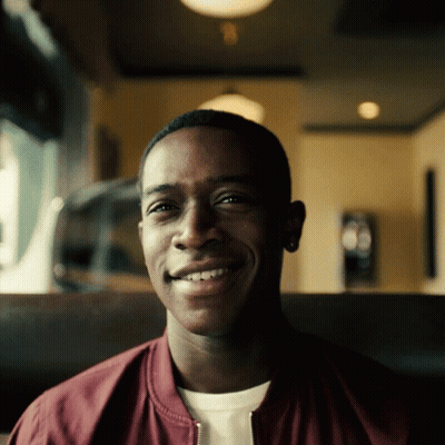 A Man Wearing A Maroon Jacket Is Smiling For The Camera GIF