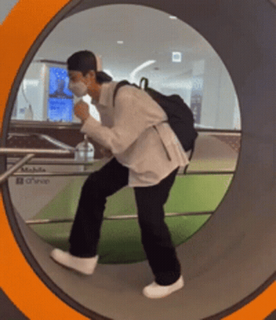 A Man Wearing A Mask And A Backpack Is Walking Through A Tunnel GIF