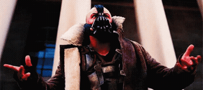 A Man Wearing A Mask And A Fur Coat Is Standing In Front Of A Building . GIF