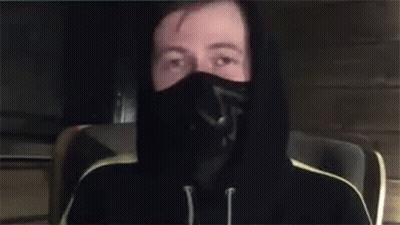 A Man Wearing A Mask And A Hoodie Is Waving His Hand . GIF