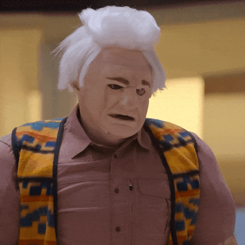A Man Wearing A Mask And A Vest With A Pattern That Says ' S ' On It GIF