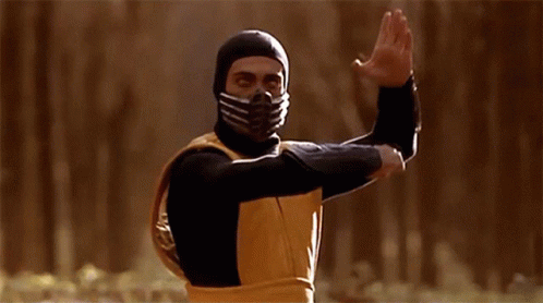A Man Wearing A Mask And A Yellow Vest Is Standing In A Forest GIF