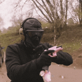 A Man Wearing A Mask And Headphones Is Holding A Pink Toy Gun GIF
