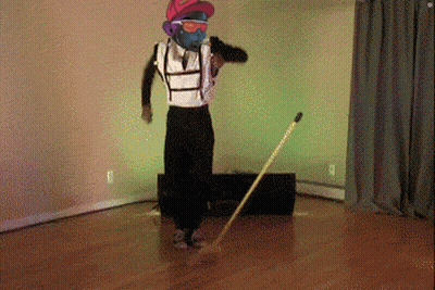 A Man Wearing A Mask And Sunglasses Is Dancing With A Broom GIF