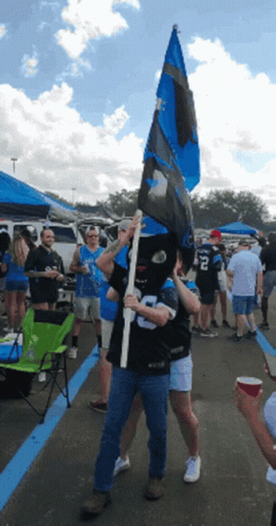 A Man Wearing A Mask Holds A Flag With A Number 8 On It GIF