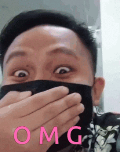 A Man Wearing A Mask Is Covering His Mouth With His Hands And The Word Omg Is On The Bottom GIF