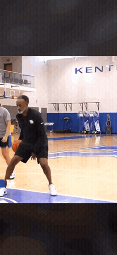 A Man Wearing A Mask Is Dribbling A Basketball On A Court In Front Of A Kentucky Sign GIF