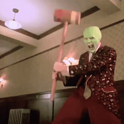 A Man Wearing A Mask Is Holding A Hammer In His Hand . GIF