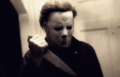 A Man Wearing A Mask Is Holding A Knife In His Hand . GIF