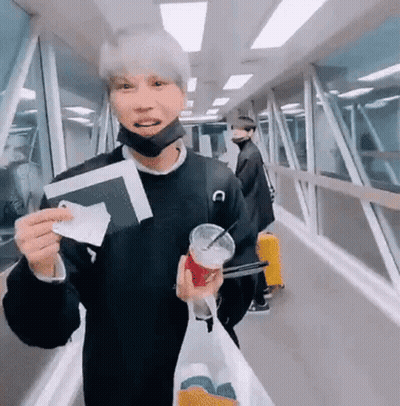 A Man Wearing A Mask Is Holding A Passport And A Cup Of Coffee . GIF