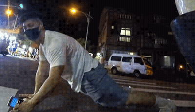A Man Wearing A Mask Is Laying On The Ground Using His Phone GIF