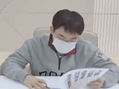 A Man Wearing A Mask Is Reading A Book . GIF