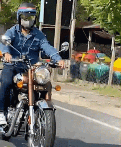 A Man Wearing A Mask Is Riding A Motorcycle GIF