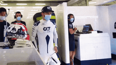 A Man Wearing A Mask Is Standing In A Garage With A Helmet . GIF