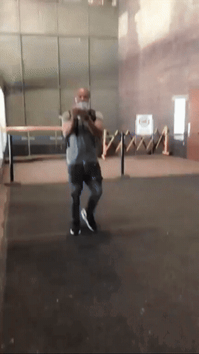 A Man Wearing A Mask Is Standing In A Room With A Fence In The Background GIF