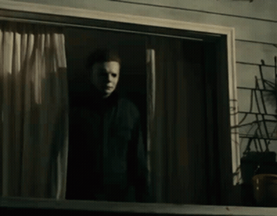 A Man Wearing A Mask Is Standing In Front Of A Window . GIF