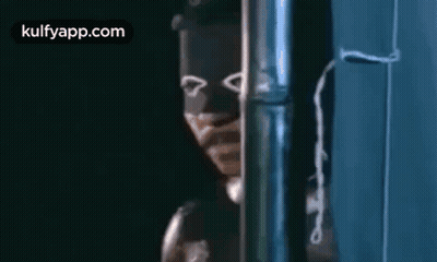 A Man Wearing A Mask Is Standing Next To A Pipe . GIF
