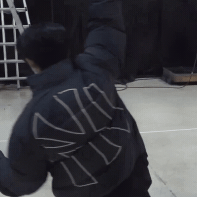 A Man Wearing A Mask Is Stretching His Arms While Another Man Looks On GIF