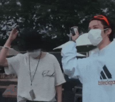 A Man Wearing A Mask Is Taking A Picture Of Another Man . GIF