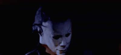 A Man Wearing A Mask Is Talking On A Cell Phone In The Dark . GIF