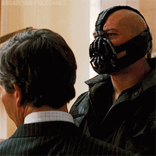 A Man Wearing A Mask Is Talking To Another Man In A Suit GIF