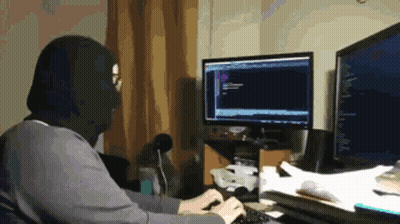 A Man Wearing A Mask Is Typing On A Keyboard In Front Of A Computer Monitor GIF