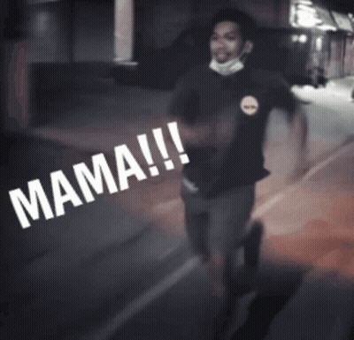 A Man Wearing A Mask Is Walking Down A Street With The Word Mama Written On The Ground GIF