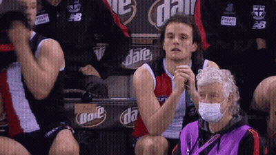 A Man Wearing A Mask Sits In A Stadium With A Sign That Says Date On It GIF