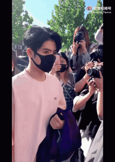A Man Wearing A Mask Stands In Front Of A Crowd GIF
