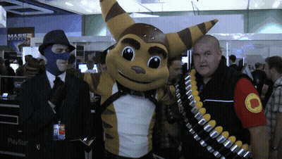 A Man Wearing A Mask Stands Next To A Raccoon Mascot And A Playstation Bag GIF