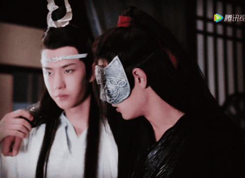 A Man Wearing A Mask Stands Next To Another Man In A White Shirt GIF