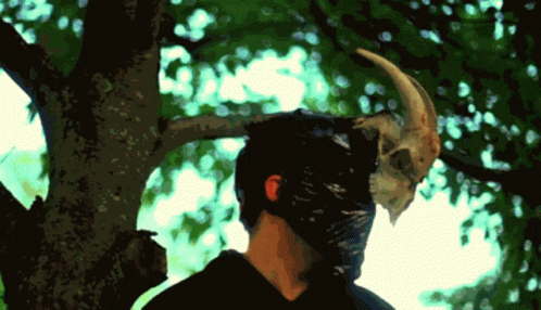 A Man Wearing A Mask With A Horn On His Head GIF