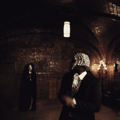 A Man Wearing A Mask With Rhinestones Is Standing In A Dark Room GIF