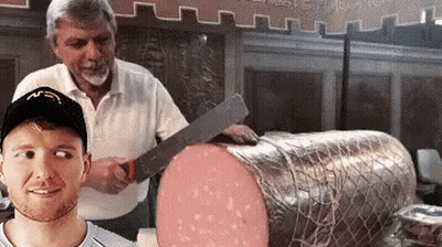 A Man Wearing A Mcdonald 'S Hat Is Standing Next To A Large Piece Of Meat GIF