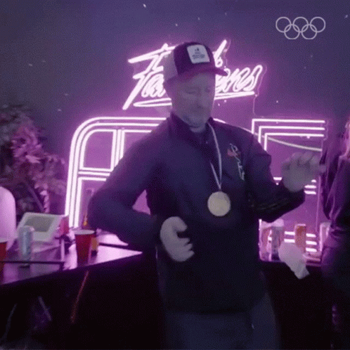 A Man Wearing A Medal Around His Neck Is Dancing GIF