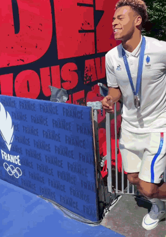A Man Wearing A Medal Is Standing In Front Of A Sign That Says France GIF