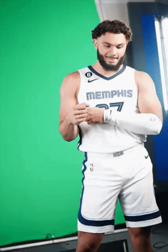 A Man Wearing A Memphis Jersey And Shorts Stands In Front Of A Green Screen GIF