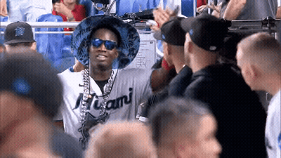 A Man Wearing A Miami Shirt And Sunglasses Stands In A Crowd GIF