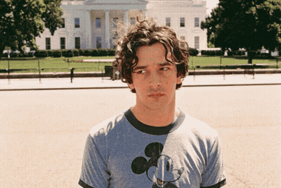 A Man Wearing A Mickey Mouse T-Shirt Stands In Front Of The White House GIF